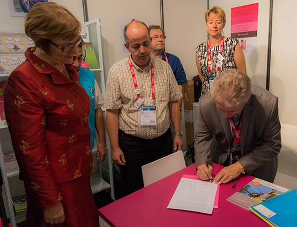 Pascal Sanz (Cfibd) signe la déclaration OMPI des associations françaises,  sous le regard de la présidente de l'IFLA Sinikka Sipilä et de Xavier Galaup, de l'IABD.