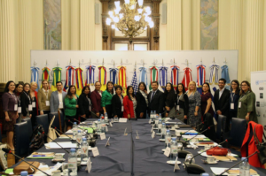 Group photo of the participants at the meeting table, with flags in the background